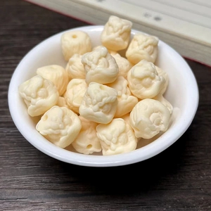 Macro shot of ivory fruit carved lion head beads in a white bowl on dark wood