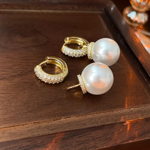 Detail of gold-plated hoop earrings with zircon pavé and large white pearl pendant
