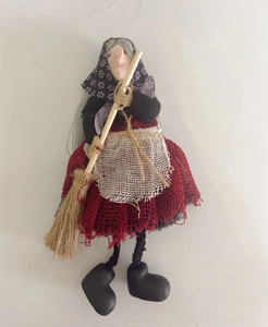 Detailed close-up of a Halloween witch doll featuring a red linen skirt and wooden broom
