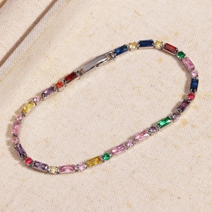 Macro detail of silver bracelet with colorful rectangular zircons on textured fabric