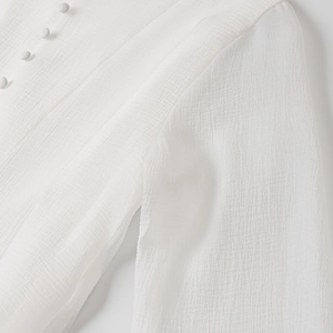Detailed view of textured crepe fabric and small white buttons on the dress neckline