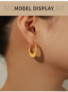 Close-up of gold-plated hoop earring with star texture pattern on a model ear