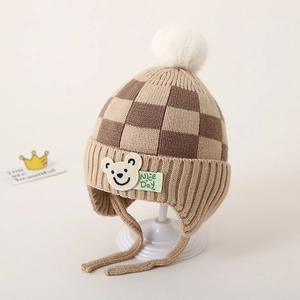 Detail van gebreide muts met dambordpatroon voor peuters met beer-patch en pompon