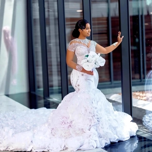 Elegant white mermaid wedding dress with beaded lace, sequins, and long ruffled train