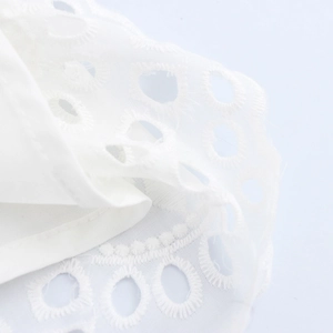 Elegante abito bianco senza maniche a girocollo con ricami e dettagli traforati