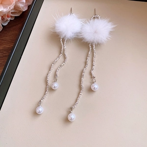 Detail of white plush pompom earrings with imitation pearls and silver metal chains