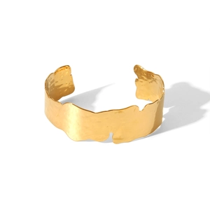 Détail d'un bracelet ouvert en titane plaqué or 18 carats avec texture martelée et bords ondulés