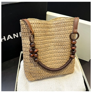 Detailed texture of brown straw woven handbag featuring a unique wooden bead handle