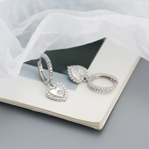 Detail of silver heart hoop earrings with micro-set zircons and star pendant