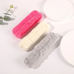 Close-up of soft coral fleece face wash wristbands and headbands in pink, cream and grey