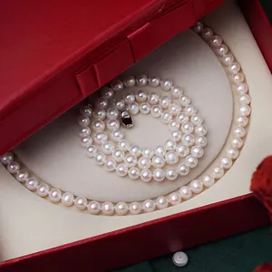 Lustrous white freshwater pearl necklace with metal clasp in a red ribbon jewelry box