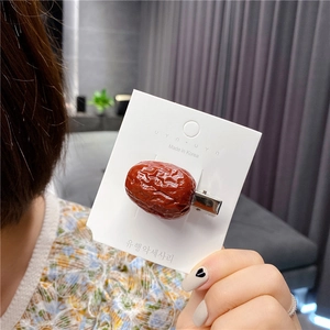 Macro detail of creative realistic red date hair clip with textured surface on card