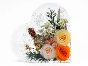Detail of heart-shaped resin mold with preserved yellow and pink roses inside
