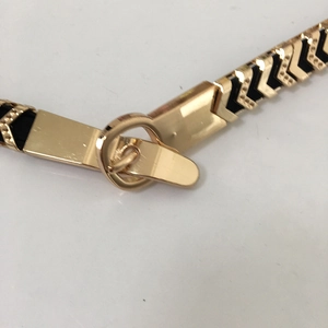 Close-up of golden metal buckle and black elastic strap on a stylish waist belt for women