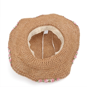Detail view of woven straw hat interior featuring beige sweatband and floral embroidery