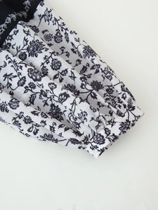 Vue macro détaillée du motif floral noir et blanc et du poignet froncé sur la manche