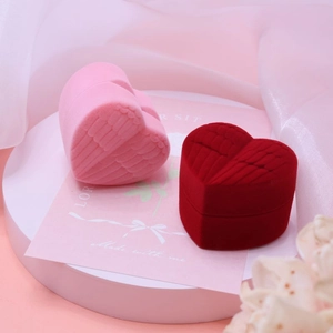 Velvet heart jewelry boxes with wing relief in pink and dark red on a white pedestal