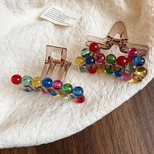 Detailed view of translucent brown acrylic hair claws with colorful beaded decorations