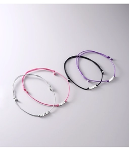 Detail of four colorful woven cord bracelets with polished silver metal cylinder accents