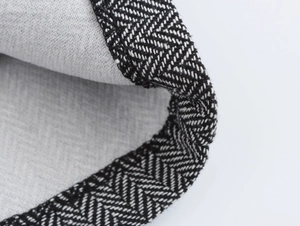 Detailed macro view of gray woven fabric texture with black and white herringbone trim