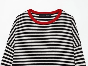 Detail of red crew neck collar and black and white striped knit fabric texture