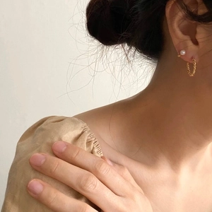 Close-up of fresh water pearl studs and gold twisted earrings worn on a female model