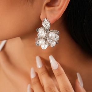 Close-up of model wearing silver flower earrings with 18K gold plating and pearls