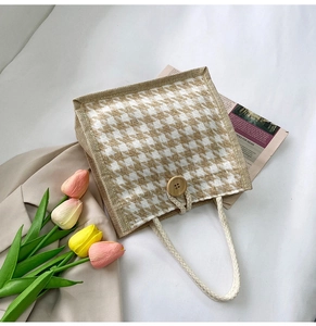 Detail view of houndstooth canvas tote bag with wooden button closure and woven rope handles