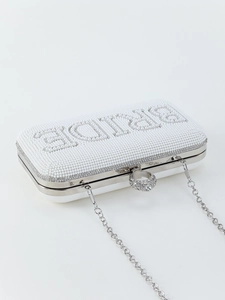 Close-up of white pearl bridal clutch with pearl-studded BRIDE text and crystal ring clasp