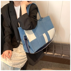 Detail of blue denim tote with H-shaped color block and dark blue shoulder strap