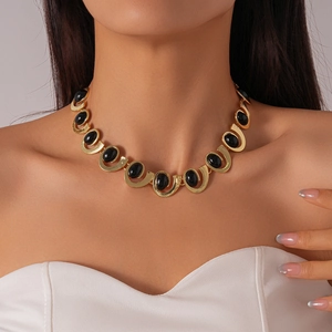 Close-up of vintage gold U-shaped link necklace with black oval stones on a model
