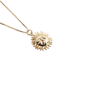Gros plan détaillé d'un collier avec pendentif soleil vintage en cuivre plaqué or