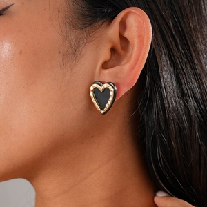 Close-up of a model wearing a vintage heart-shaped earring in gold and black finish