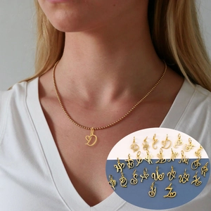 Polished gold heart-shaped letter necklace with ball chain worn by a female model
