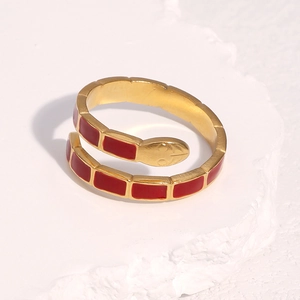 Macro detail of gold snake ring with red enamel inlay and engraved head textures