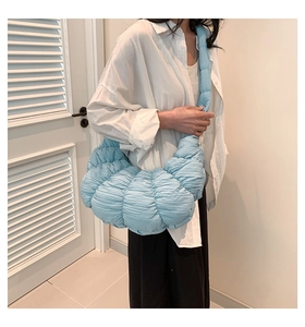 Detail of light blue pleated dumpling bag featuring soft padded texture and wide shoulder strap