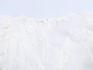 Close-up of white mesh dress back featuring floral embroidery and invisible zipper