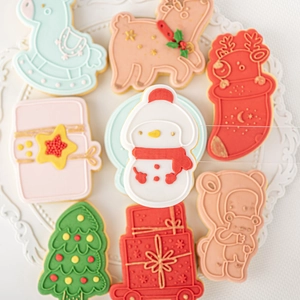 Christmas cookie cutter set featuring snowman reindeer and tree shapes on a white plate