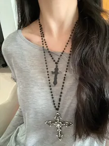Detail of layered gothic necklace featuring a black bead chain with dual cross pendants
