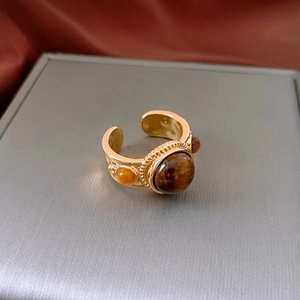 Dettaglio macro dell'anello vintage dorato con pietra occhio di tigre e bordi perlati
