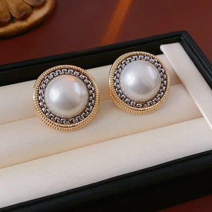 Détail de boucles d'oreilles rondes vintage avec perle et cadre en chaîne bicolore