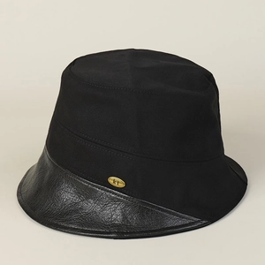 Detail of black cotton bucket hat showing leather brim stitching and gold logo plate