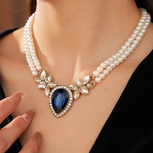 Détail d'un collier de perles double épaisseur avec gemme bleue en poire et strass