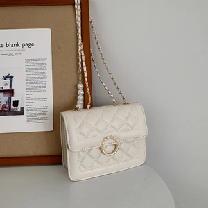 Detail of cream quilted PU bag with pearl ring buckle and golden chain strap