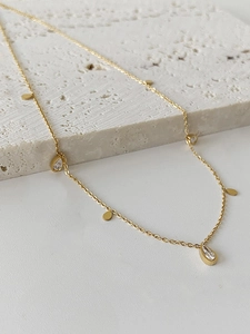 Close-up of gold tassel necklace with water drop zircons and smooth discs on stone