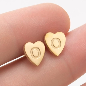 Gros plan d'une boucle d'oreille cœur dorée avec gravure circulaire sur métal poli brillant