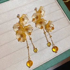 Elegant amber flower tassel earrings with resin petals and golden chains on jewelry box
