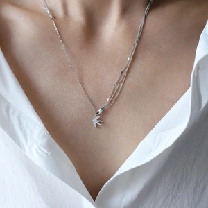Collier hirondelle argenté multicouche sur mannequin avec chaînes fines en acier titane