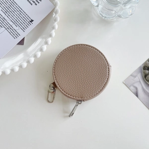 Khaki round leather coin purse with litchi pattern and metal hook on white desk