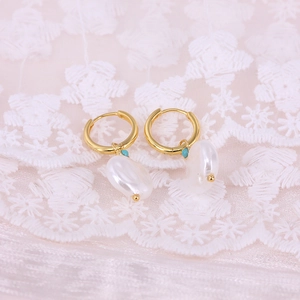 Close-up of golden hoop earrings with white baroque pearls and turquoise bead accents